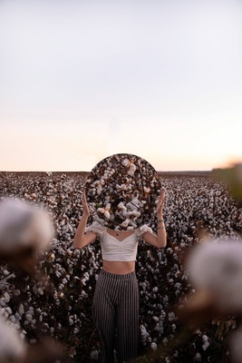 woman standing on flower field holding a mirror