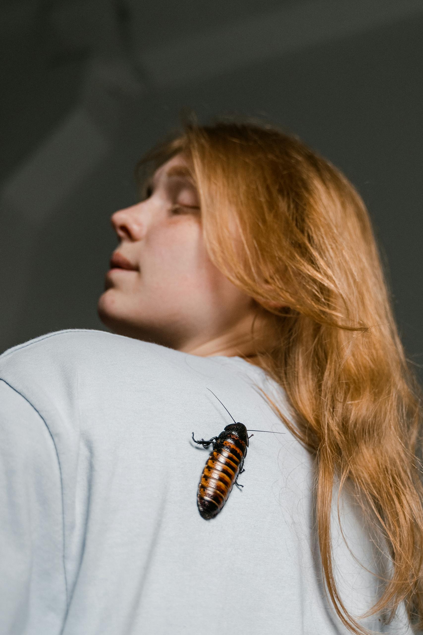 A woman with a Madagascar hissing cockroach on her shoulder, symbolizing fear or phobia.